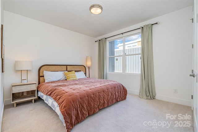 bedroom with light colored carpet and baseboards