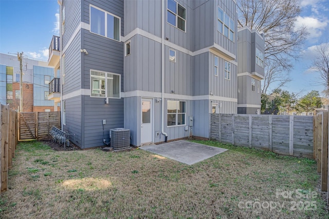 back of house with a lawn, cooling unit, board and batten siding, and a fenced backyard