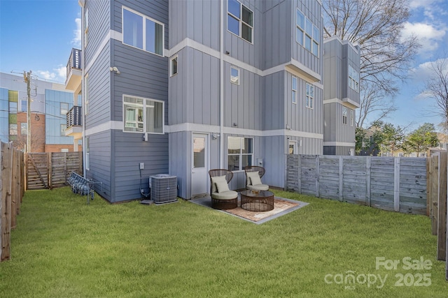 rear view of house featuring central air condition unit, a yard, board and batten siding, and a fenced backyard