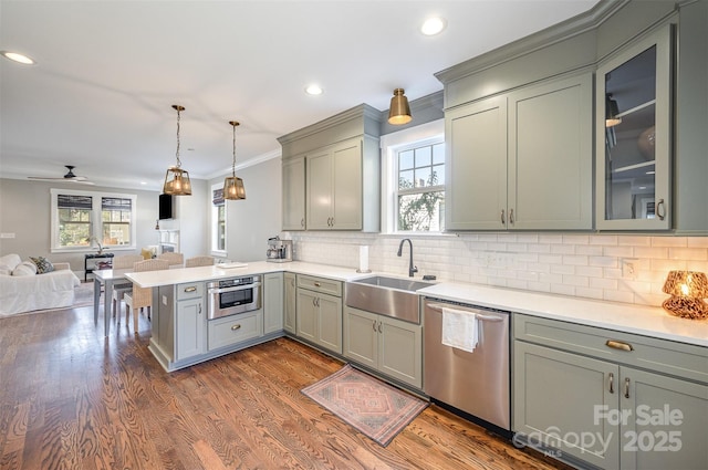 kitchen with dark wood-type flooring, open floor plan, dishwasher, a peninsula, and a sink