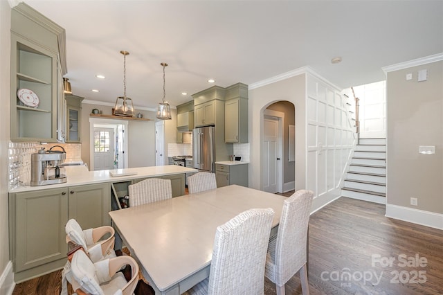 dining area featuring baseboards, arched walkways, dark wood-style flooring, ornamental molding, and stairs