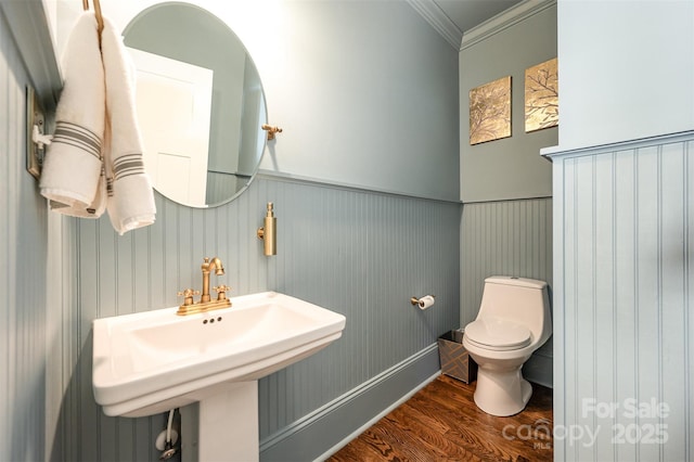 bathroom with wood finished floors, a sink, ornamental molding, wainscoting, and toilet