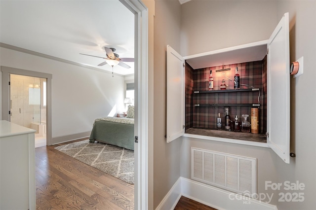 interior space featuring visible vents, baseboards, ceiling fan, and wood finished floors