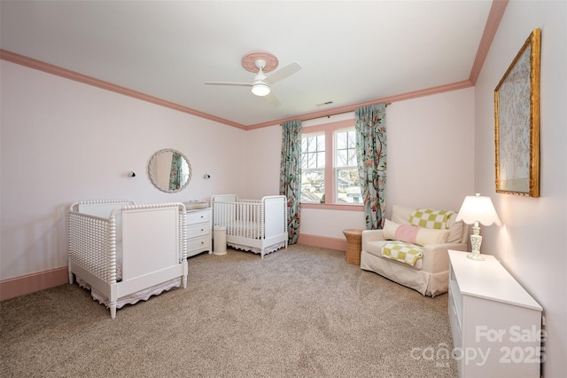 carpeted bedroom featuring visible vents, a nursery area, baseboards, and ornamental molding