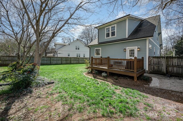 back of house with a deck, a lawn, roof with shingles, and a fenced backyard