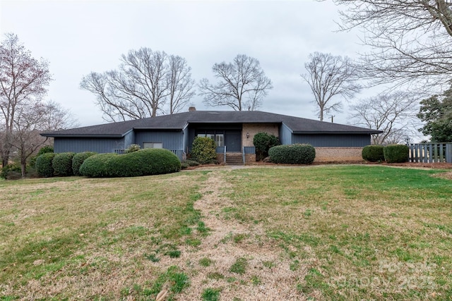 mid-century inspired home with brick siding, a chimney, and a front yard