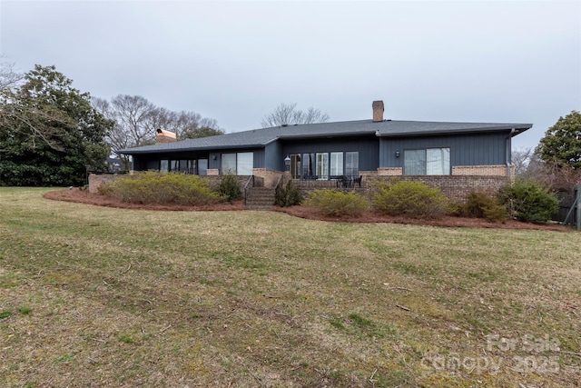 view of front of house with brick siding, a front yard, and a chimney