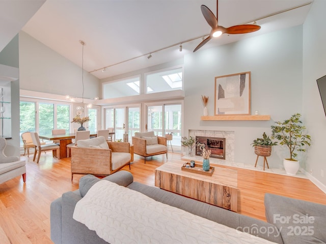 living area featuring a high end fireplace, plenty of natural light, high vaulted ceiling, and wood finished floors