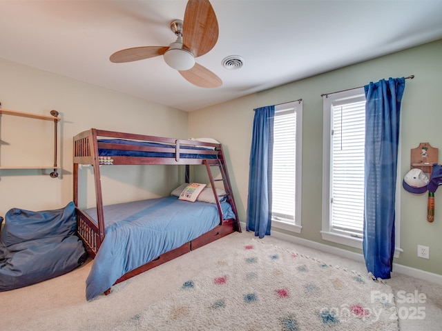 carpeted bedroom featuring visible vents, multiple windows, baseboards, and a ceiling fan