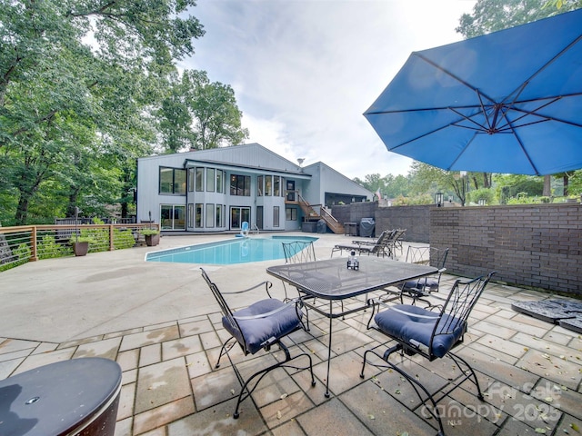 view of swimming pool featuring stairway, fence, a fenced in pool, and a patio area