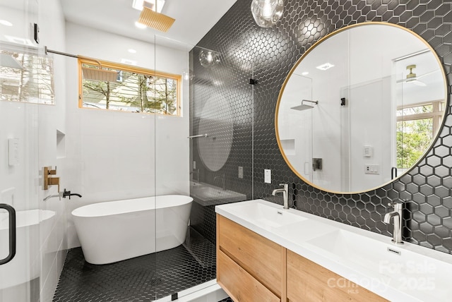 bathroom featuring tile walls, a healthy amount of sunlight, a shower stall, and a sink