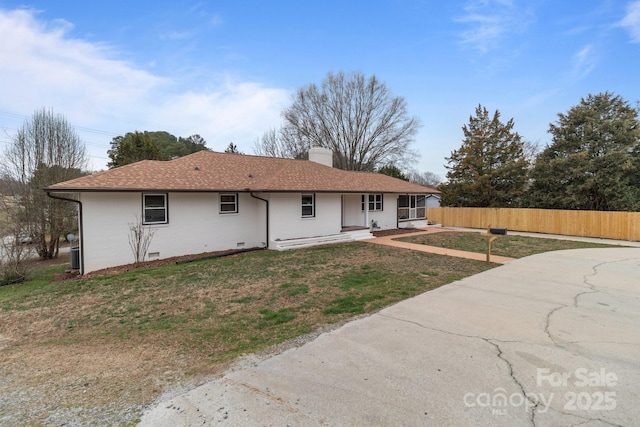 rear view of house with fence, roof with shingles, a chimney, crawl space, and a lawn