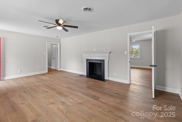 unfurnished living room with visible vents, a tile fireplace, a ceiling fan, and wood finished floors