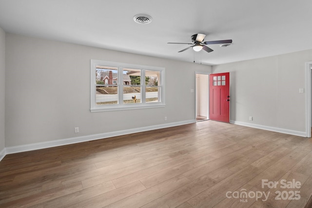 spare room featuring ceiling fan, visible vents, baseboards, and wood finished floors