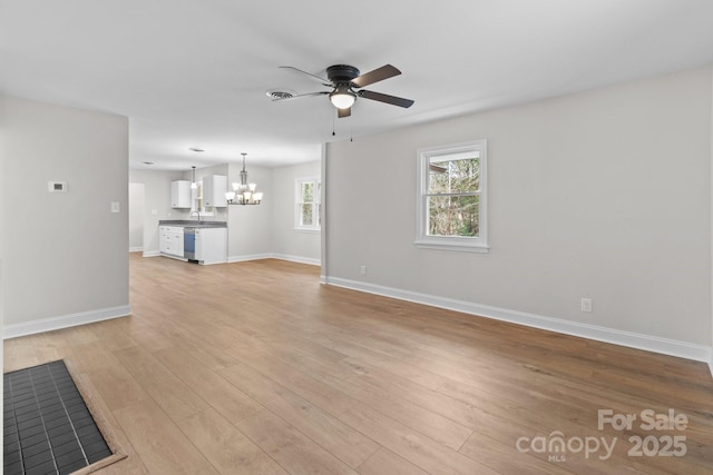 unfurnished living room featuring visible vents, ceiling fan with notable chandelier, light wood-type flooring, and baseboards