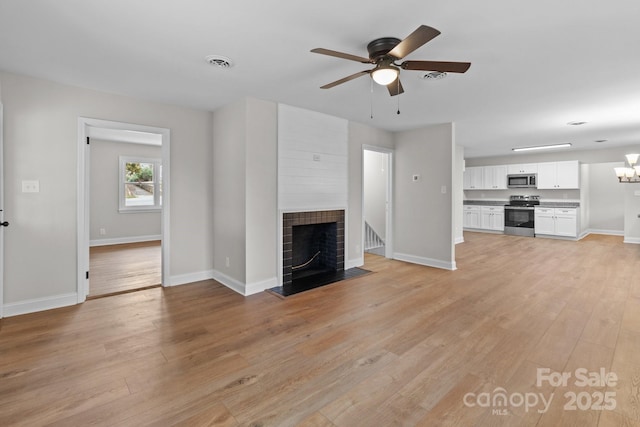 unfurnished living room with a fireplace, baseboards, and light wood-style floors