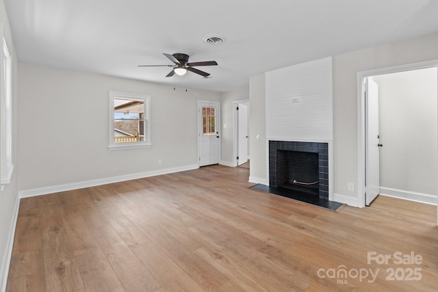 unfurnished living room featuring light wood-style flooring, a fireplace, visible vents, and baseboards