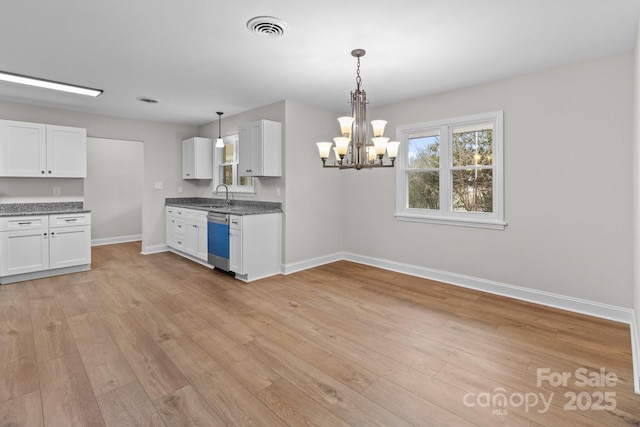 kitchen with light wood-type flooring, visible vents, stainless steel dishwasher, white cabinetry, and baseboards