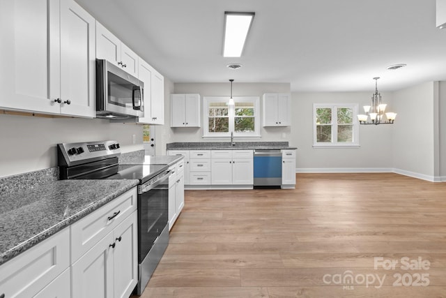 kitchen with a sink, white cabinetry, light wood finished floors, and stainless steel appliances