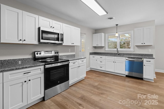 kitchen with visible vents, light wood-style flooring, white cabinets, and stainless steel appliances