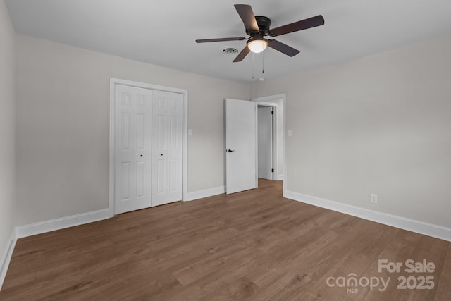 unfurnished bedroom with a closet, visible vents, baseboards, and wood finished floors