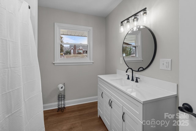 bathroom with vanity, plenty of natural light, wood finished floors, and baseboards