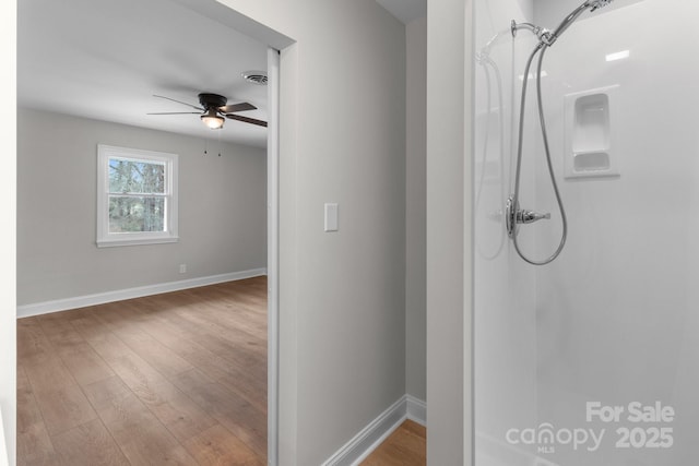 bathroom featuring wood finished floors, visible vents, baseboards, ceiling fan, and a shower