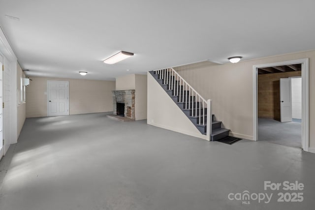 finished basement featuring a stone fireplace and stairway