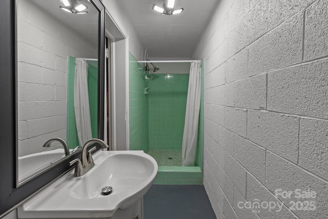 bathroom with a shower stall, vanity, and concrete block wall