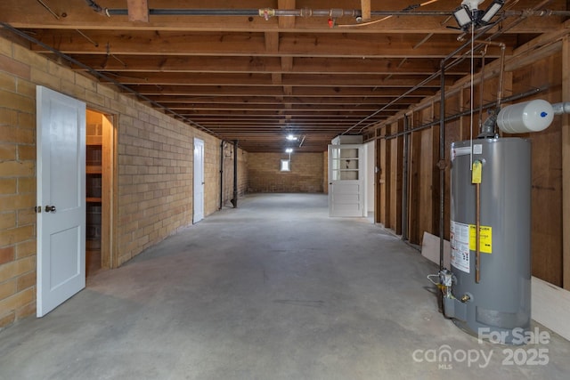 below grade area featuring brick wall and water heater