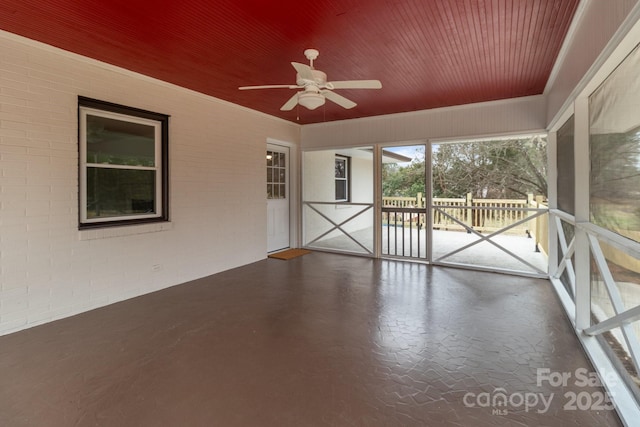 unfurnished sunroom featuring wooden ceiling and a ceiling fan