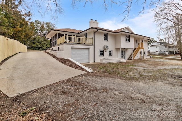 view of home's exterior with driveway, fence, an attached garage, a sunroom, and a chimney