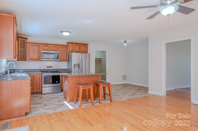 kitchen with visible vents, a sink, a kitchen breakfast bar, a kitchen island, and appliances with stainless steel finishes