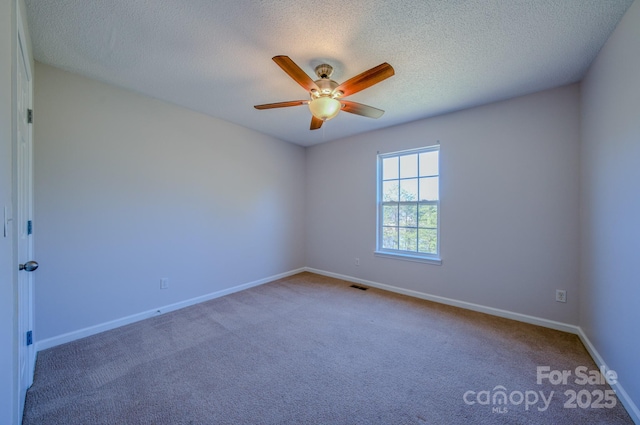 empty room featuring a ceiling fan, baseboards, visible vents, carpet floors, and a textured ceiling