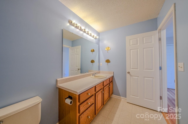 bathroom with vanity, baseboards, lofted ceiling, a textured ceiling, and toilet