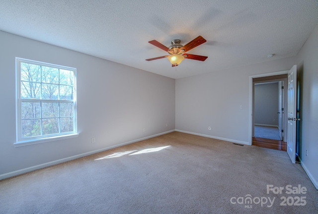 carpeted empty room with visible vents, a textured ceiling, and baseboards