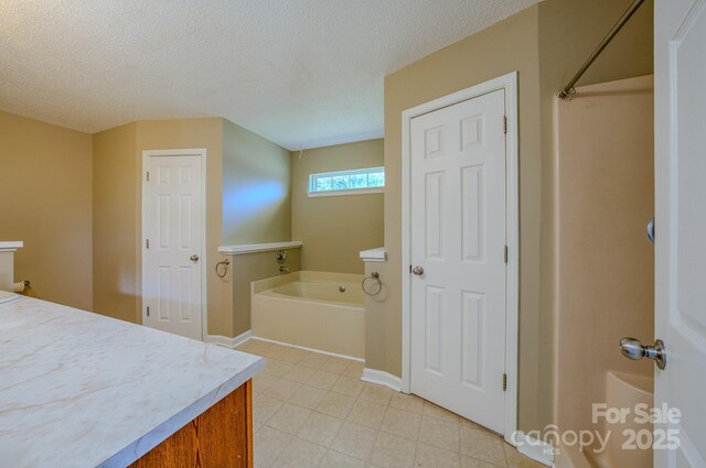 bathroom with vanity, baseboards, a textured ceiling, tile patterned floors, and a bath