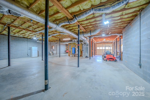 below grade area with heating unit, concrete block wall, and freestanding refrigerator