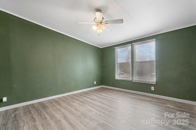 spare room featuring ceiling fan, baseboards, and wood finished floors