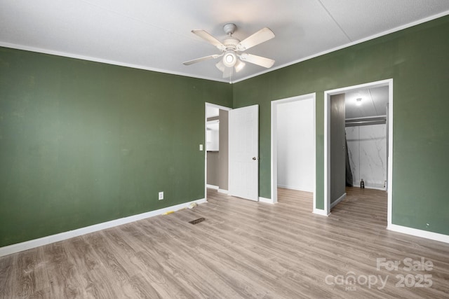 unfurnished bedroom with ornamental molding, baseboards, and wood finished floors