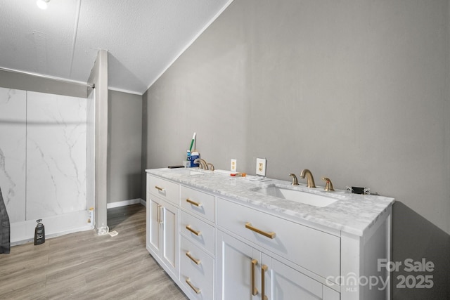 laundry area with baseboards, a textured ceiling, light wood-style floors, and a sink