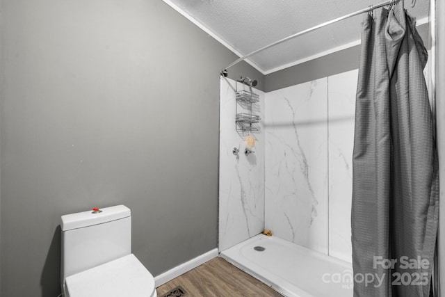 bathroom with toilet, ornamental molding, wood finished floors, a shower with shower curtain, and baseboards