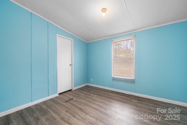 unfurnished bedroom with visible vents, baseboards, lofted ceiling, and wood finished floors