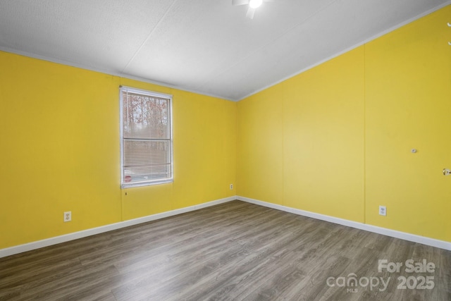 spare room featuring baseboards and wood finished floors