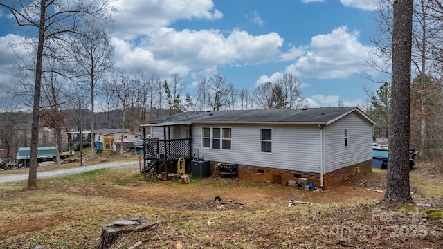 rear view of house featuring central air condition unit, driveway, and crawl space