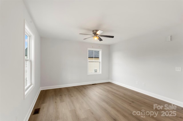 empty room featuring baseboards, wood finished floors, visible vents, and ceiling fan