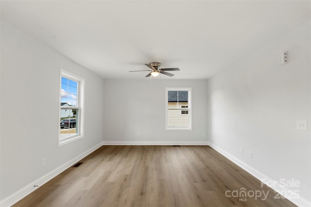 empty room with wood finished floors, baseboards, a wealth of natural light, and ceiling fan