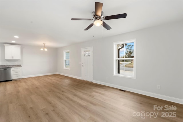 unfurnished living room featuring plenty of natural light, baseboards, and light wood-style floors