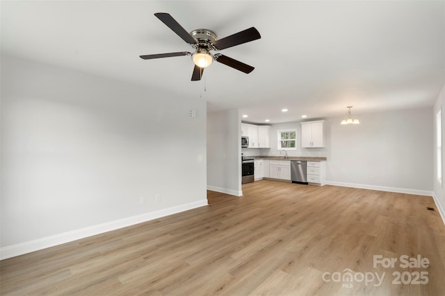 unfurnished living room featuring recessed lighting, baseboards, light wood-style floors, and a sink