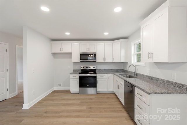 kitchen with light stone countertops, recessed lighting, a sink, stainless steel appliances, and white cabinets